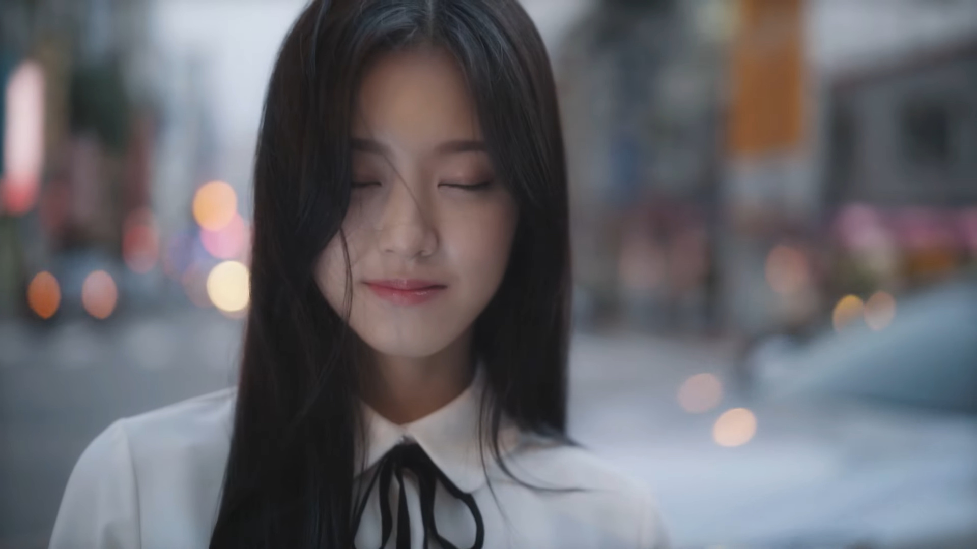 Hyunjin standing with her eyes closed.